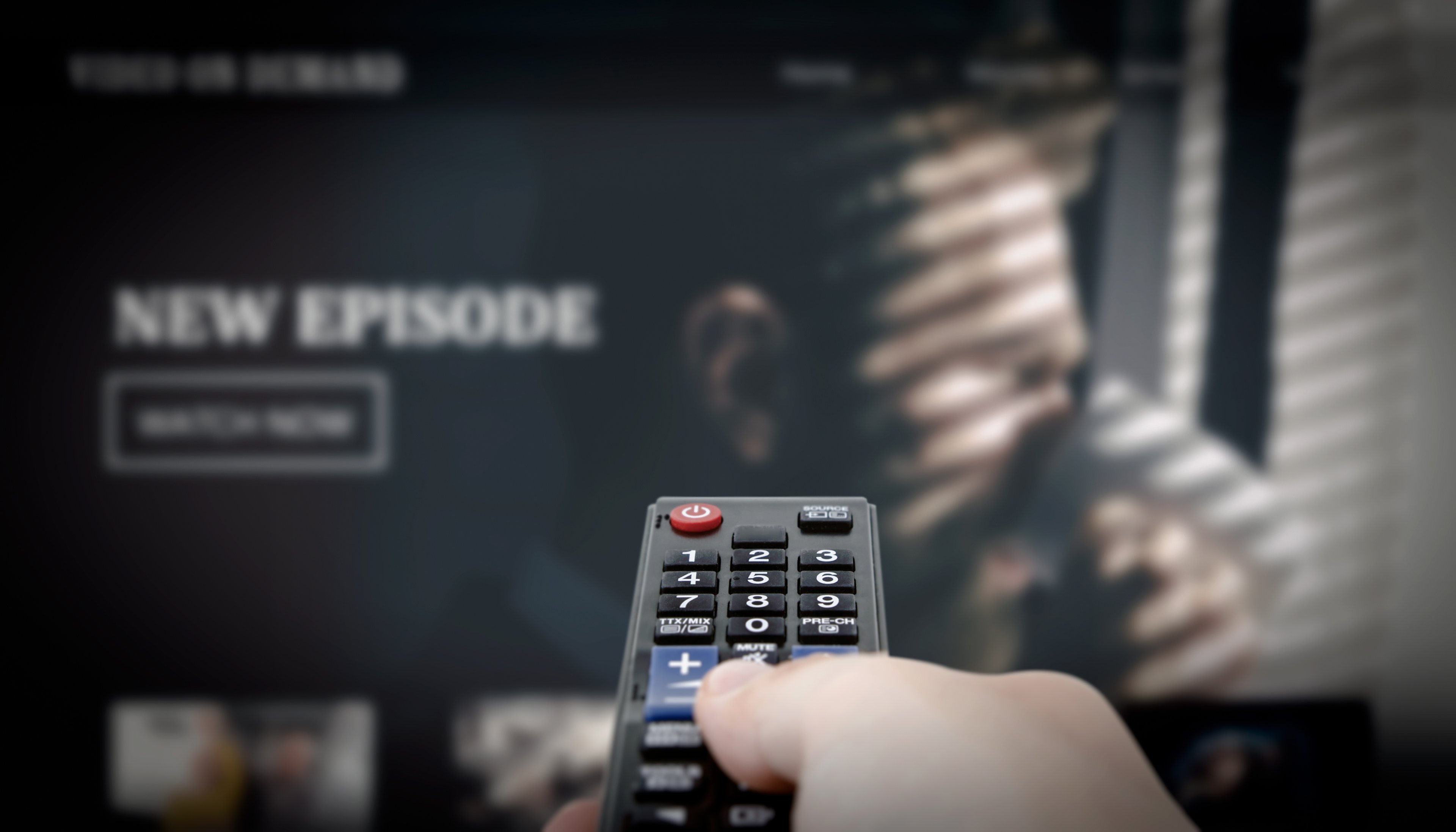 right hand holding a remote watching streaming service on TV