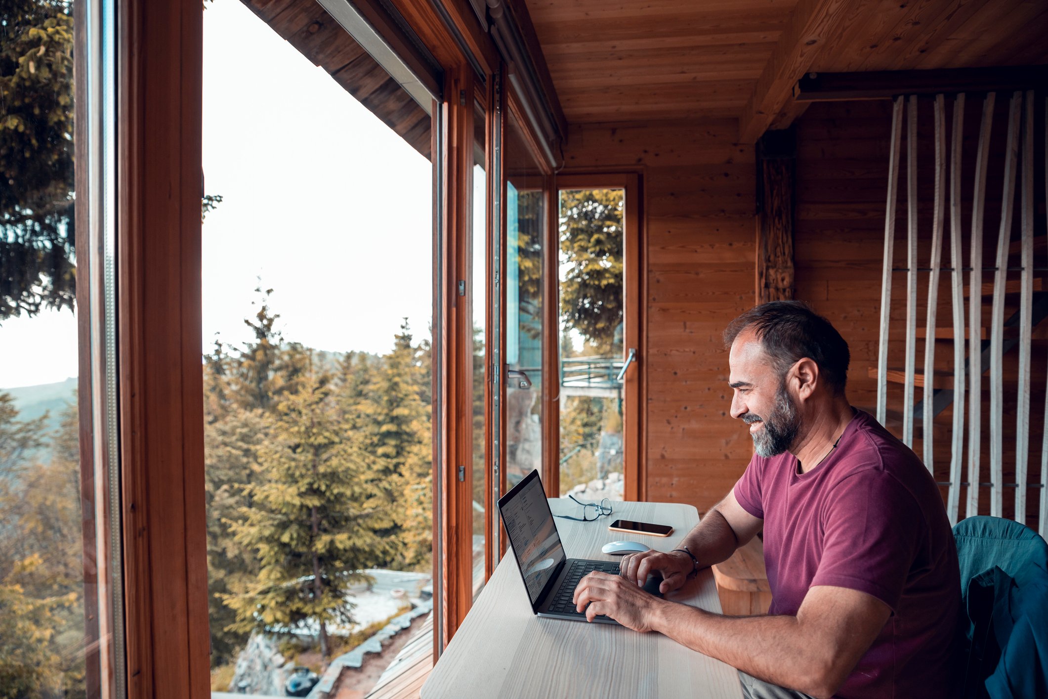 A remote worker using a computer while sitting in a home with a scenic view.