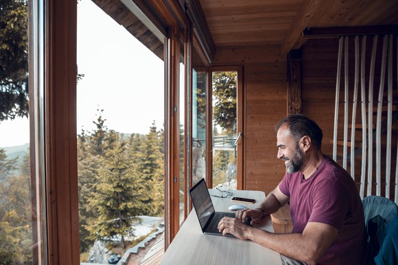 A remote worker using a computer while sitting in a home with a scenic view.
