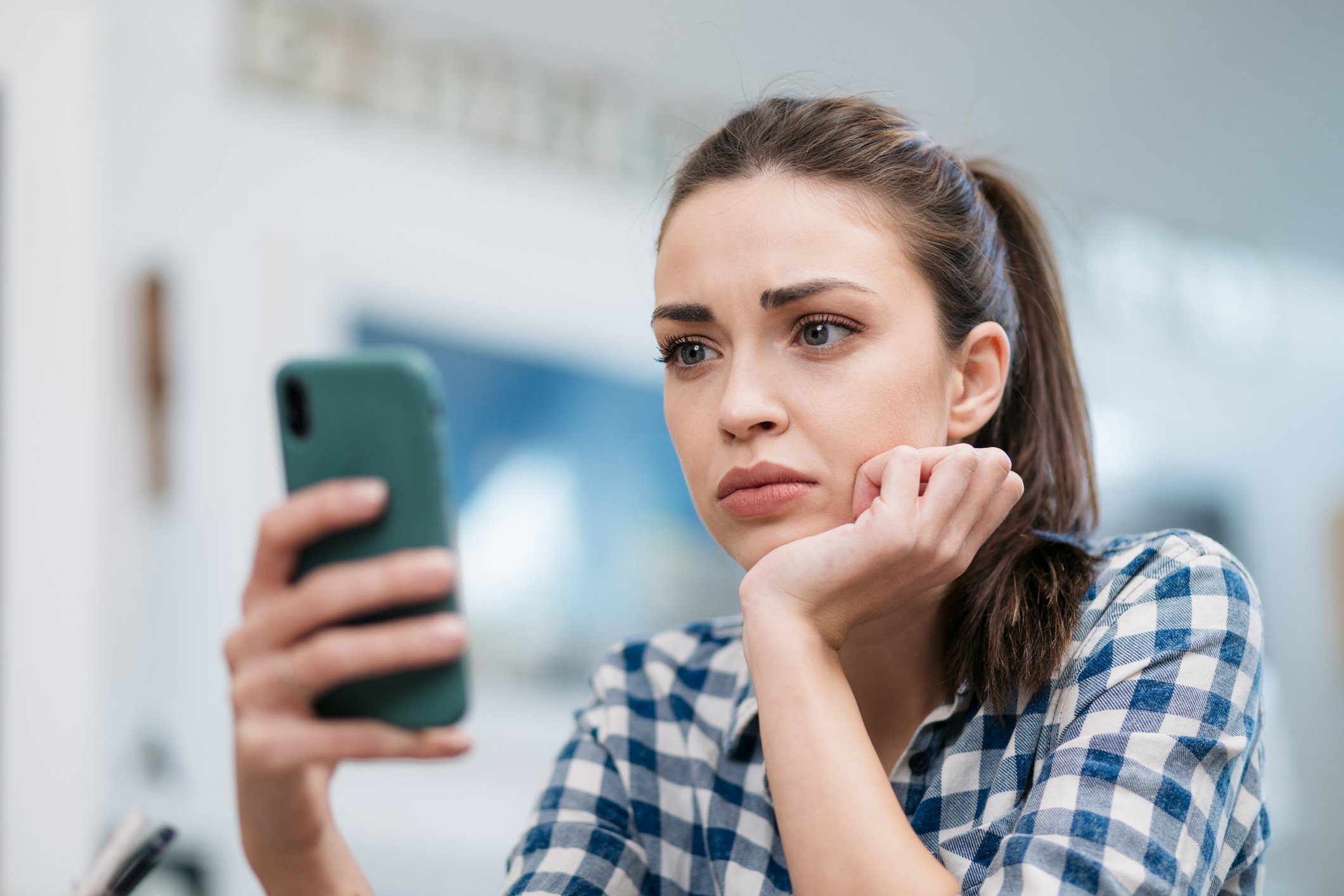 A person appears sad while looking at their phone.