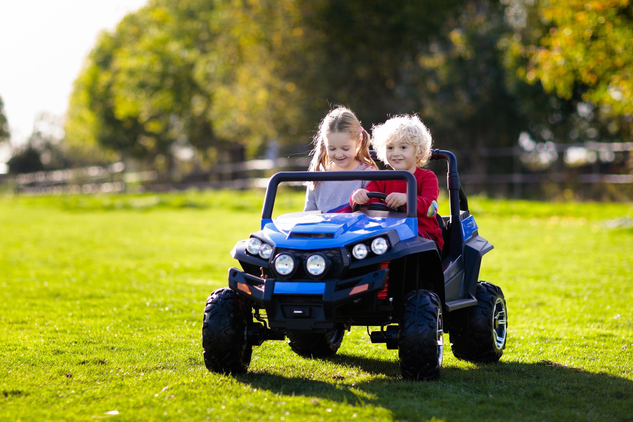 Two smiling kids in a battery powered toy truck.