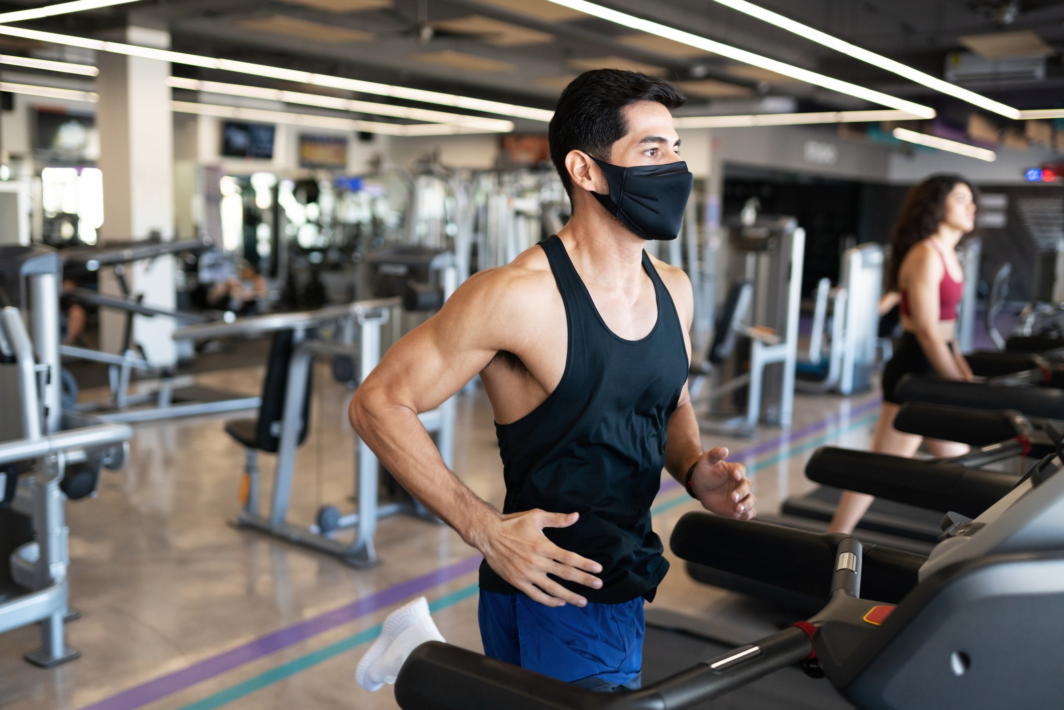 Two people running on treadmills at a gym.