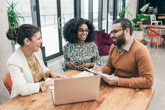 A loan officer works with a couple in a bank setting on a loan application
