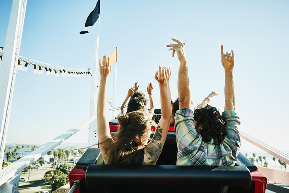 A group of people on a roller coaster ride with their hands up in the air.