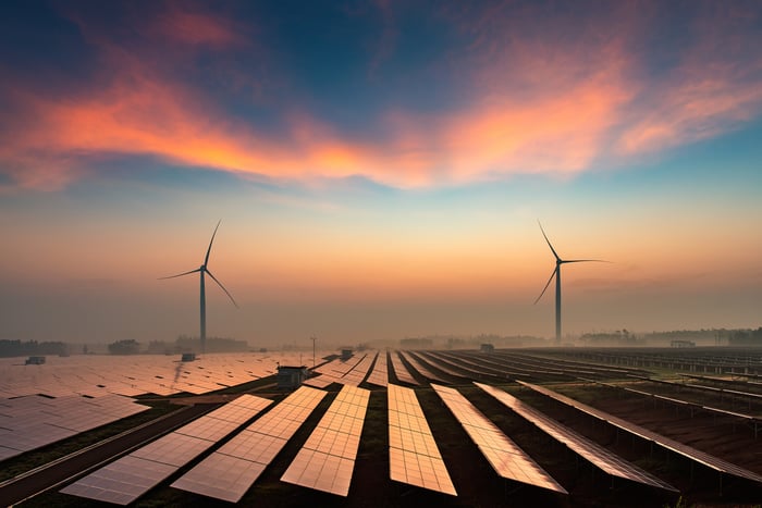 Solar power plant with wind turbines in the background. 