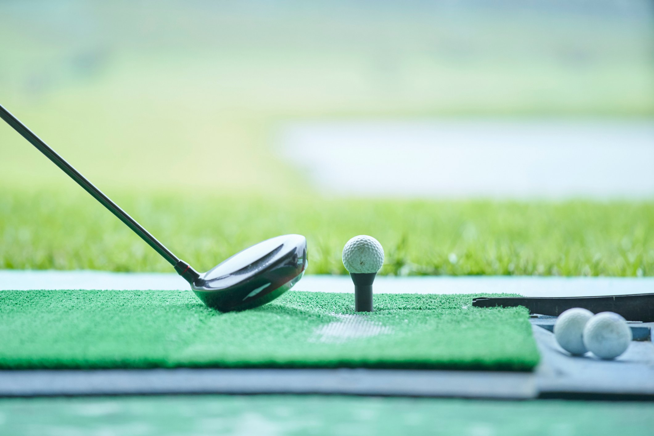 A club setting up to hit a golf ball at a driving range.