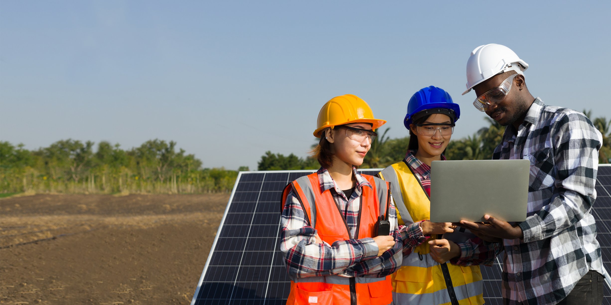 Engineers installing solar panels in a field.
