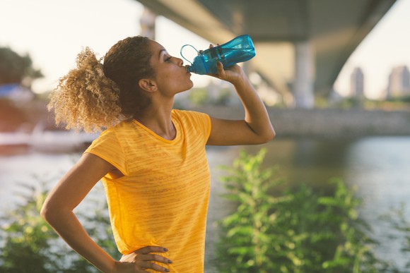 A person drinks from a water bottle outside.