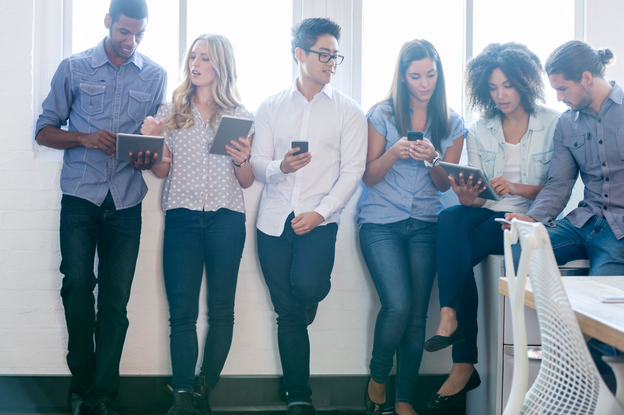 A group of people looking at cell phones and digital tablets.
