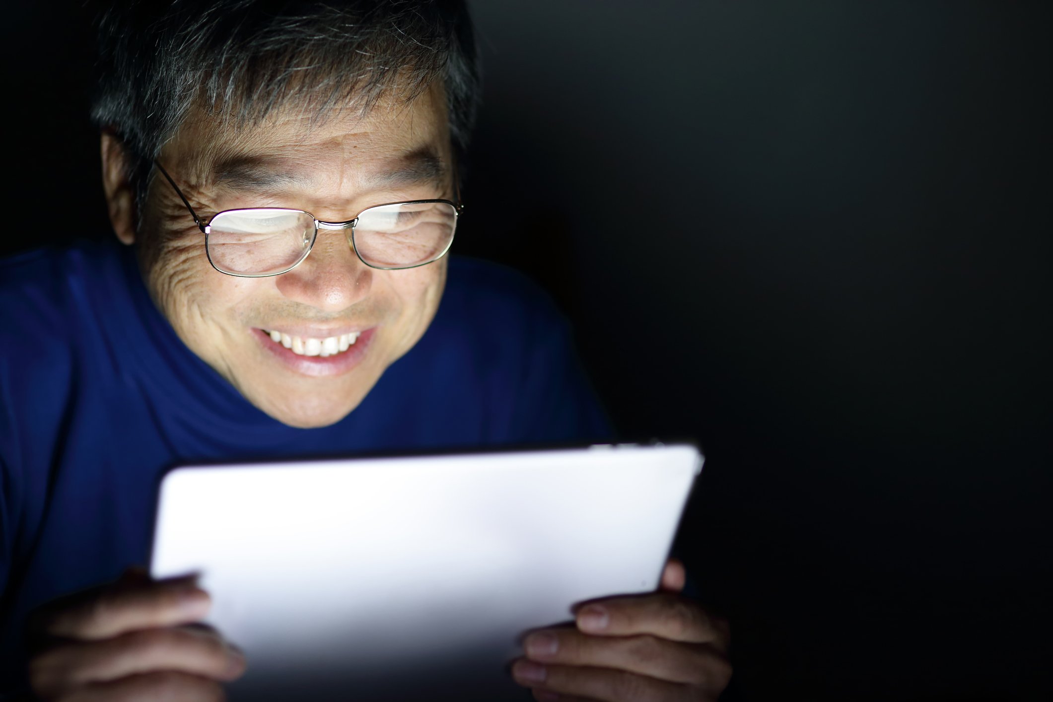 Person smiling at glowing tablet computer.