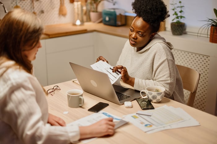 Two people sitting across the table from each other looking at financial documents.