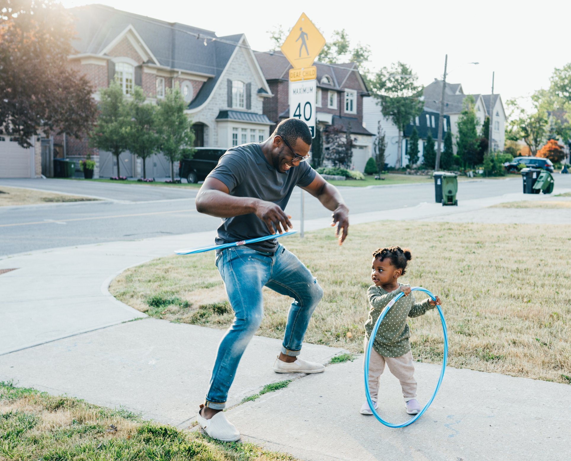 Adult and child hula-hooping in the neighborhood.
