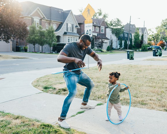 Adult and child hula-hooping in the neighborhood.
