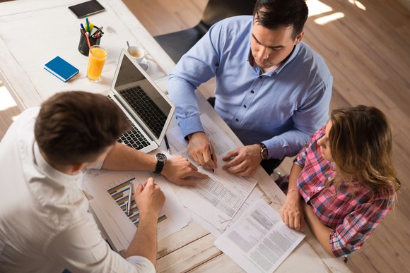 Three people at a table looking at charts.