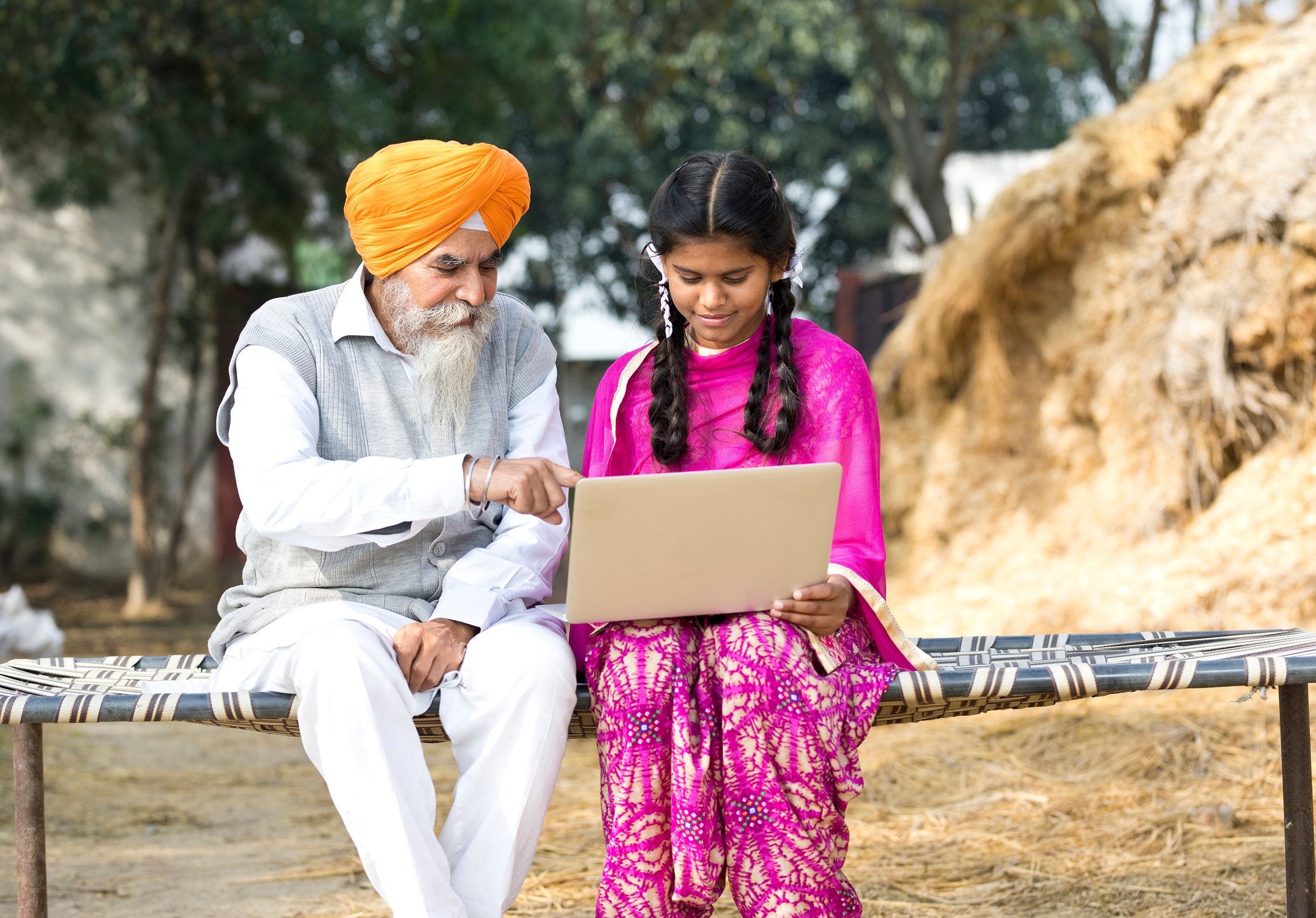 Two people sitting down and looking at a laptop.