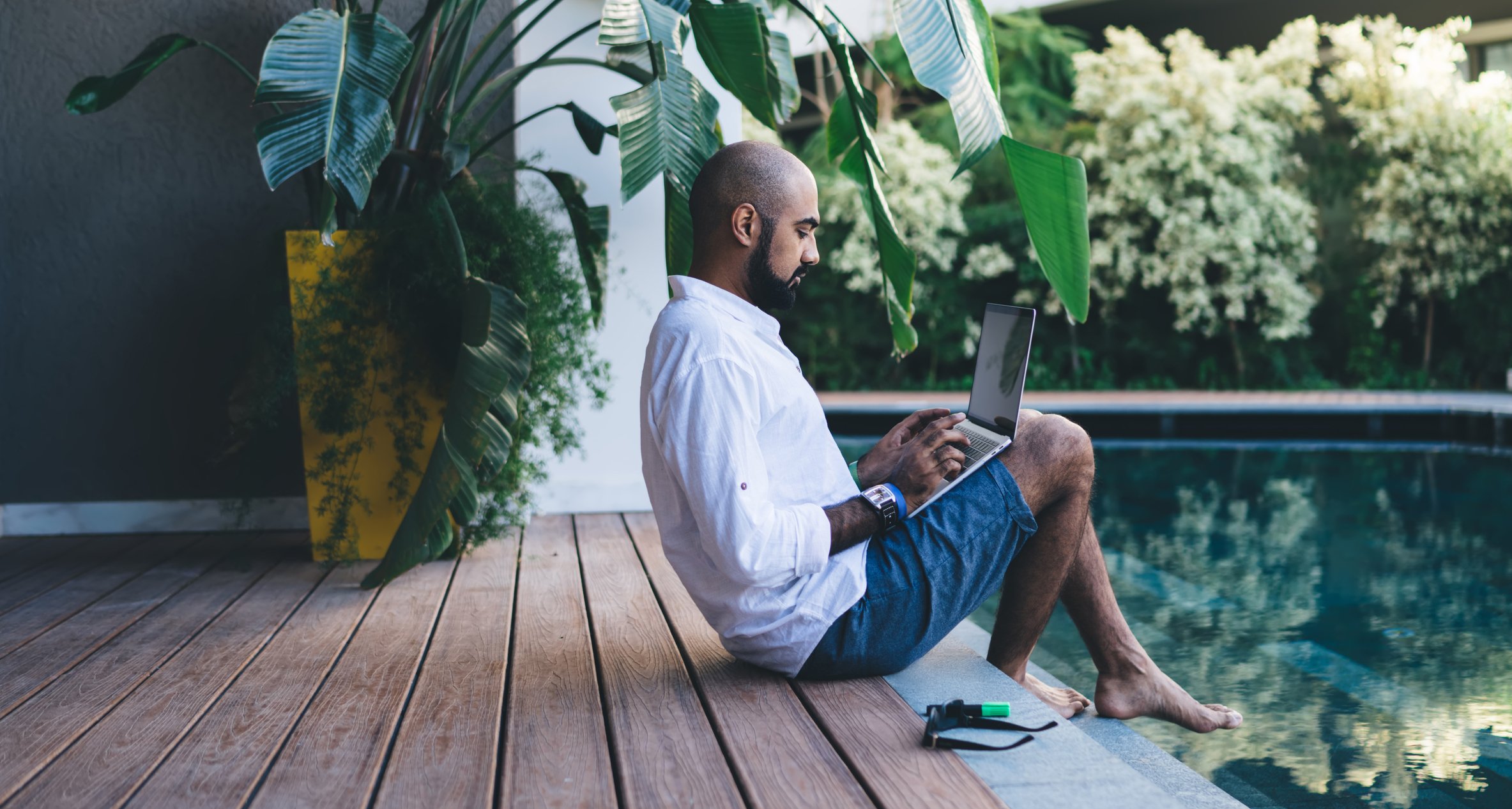 A person using a laptop by a pool.