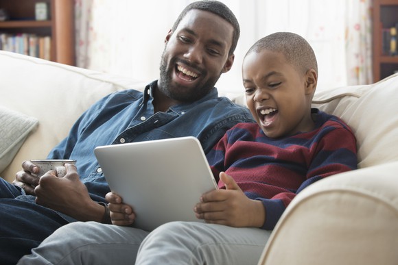 A father and son enjoying entertainment on a tablet.