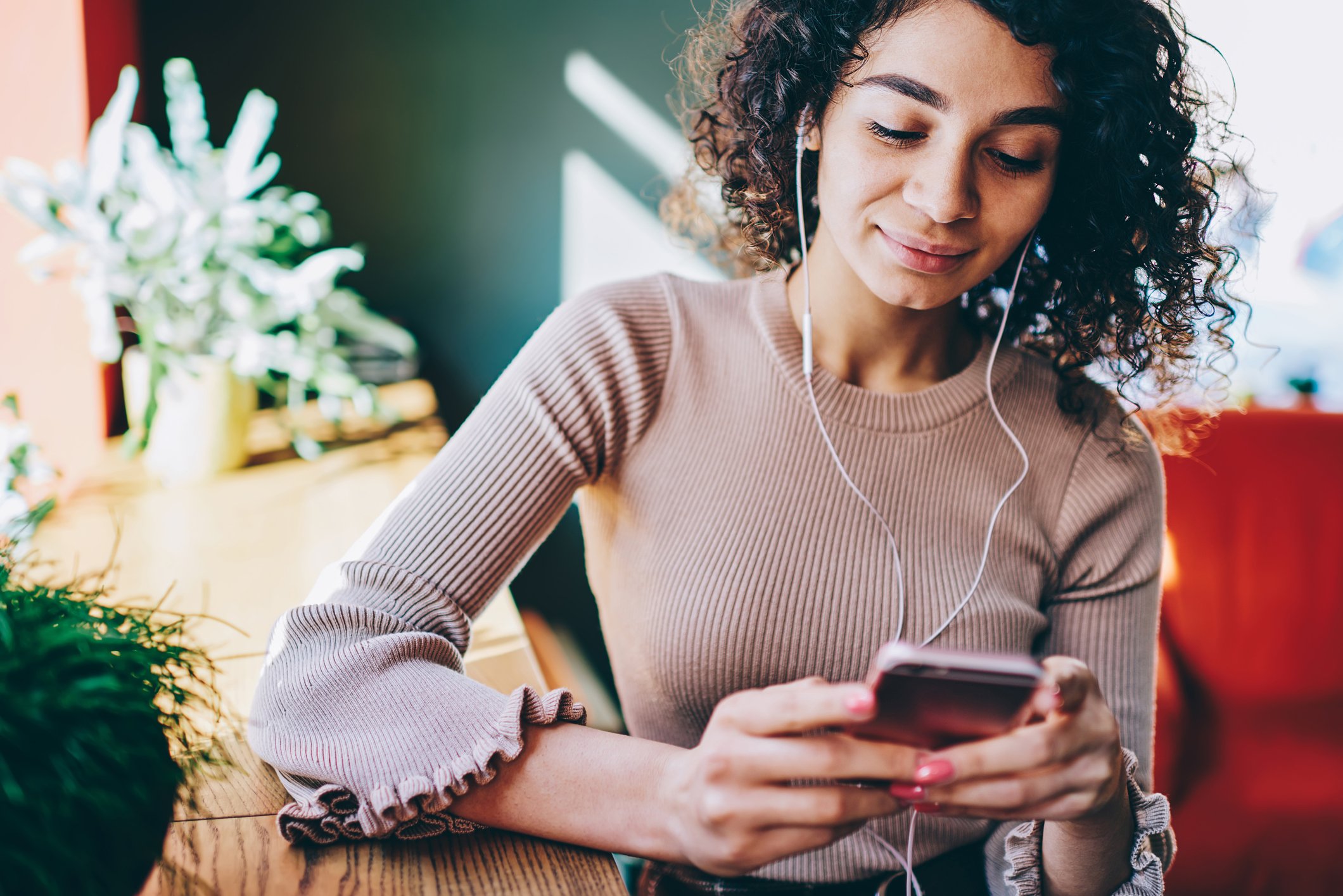 A woman wearing headphones looking at a smartphone.