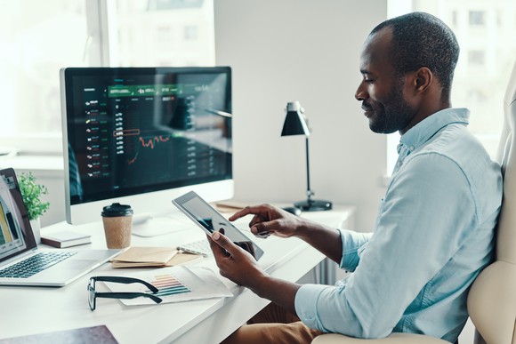 A man reviews his investments on his computer and tablet.