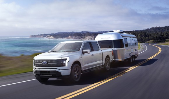 A silver F-150 Lightning, a full-size electric pickup truck, towing an Airstream trailer. 