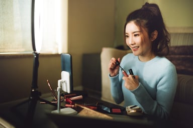 An Asian woman putting on makeup