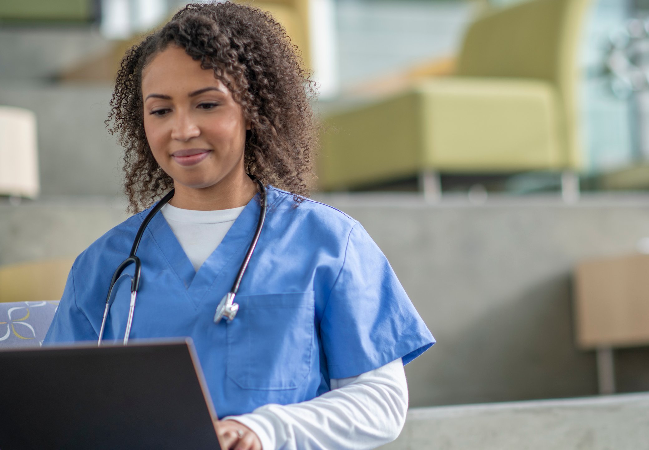 A medical professional performs work tasks on a laptop.