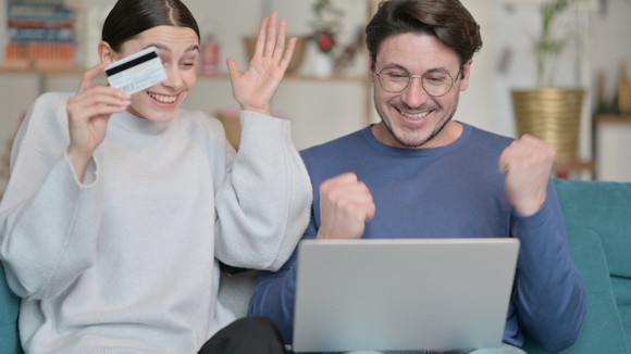 Two people looking at a laptop and cheering. 