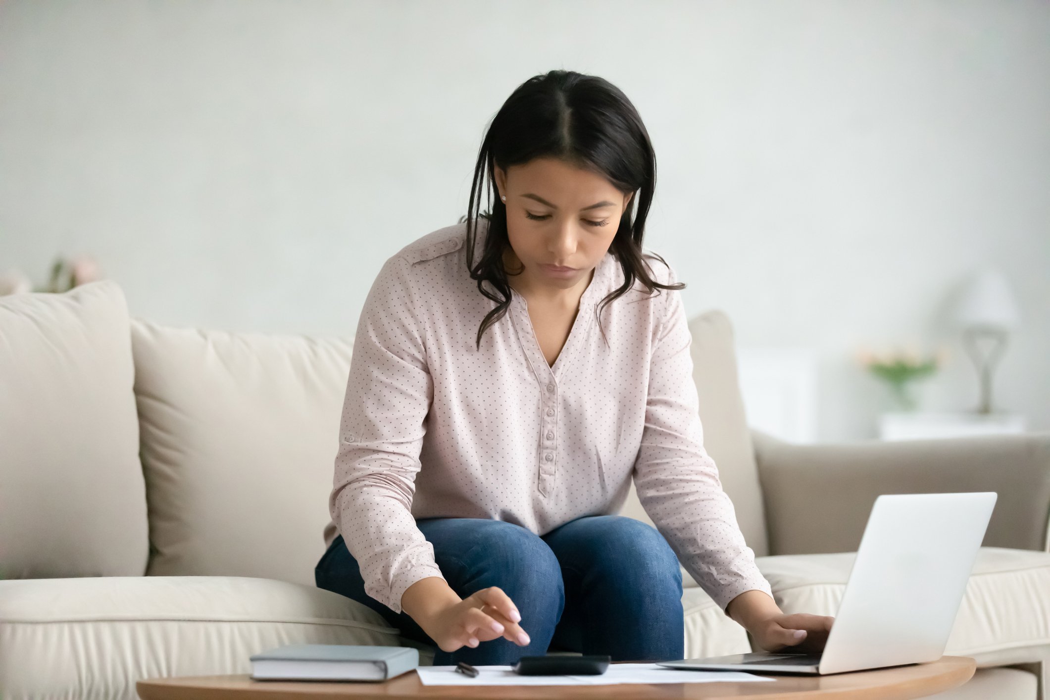 Doing math with a laptop and calculator at the living room table.