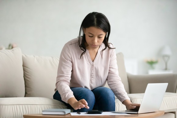 Doing math with a laptop and calculator at the living room table.