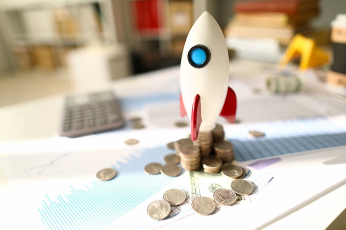 Model rocket sitting on stacks of coins.