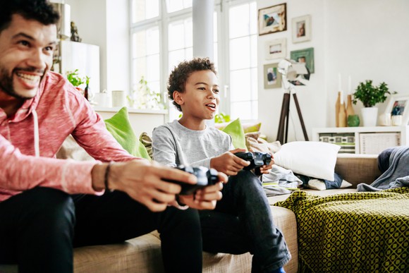 An adult playing a video game with a child.