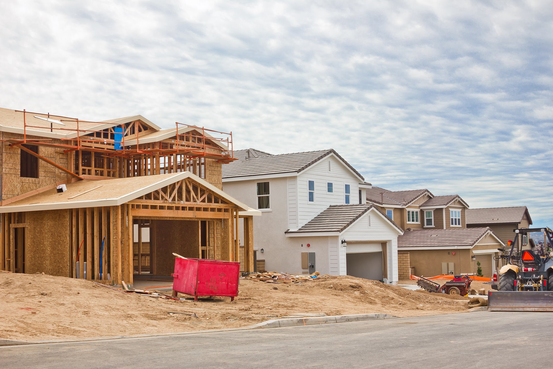 Several homes are in various phases of construction on a street.
