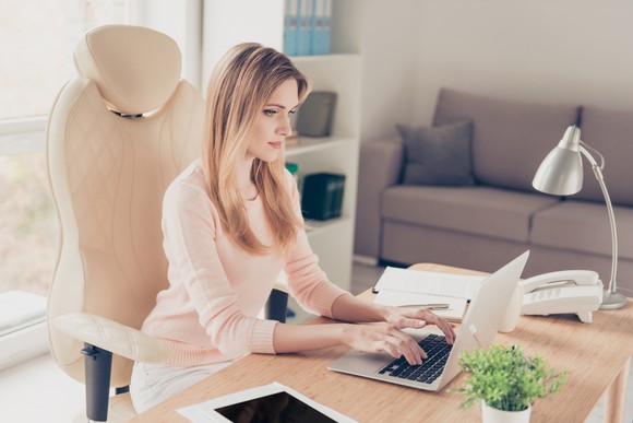 Businessperson sitting at desk and typing on computer.