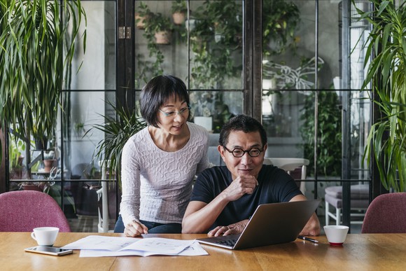 A couple looks at a laptop as they plan retirement finances.
