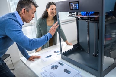 A man and woman use a 3D printer.