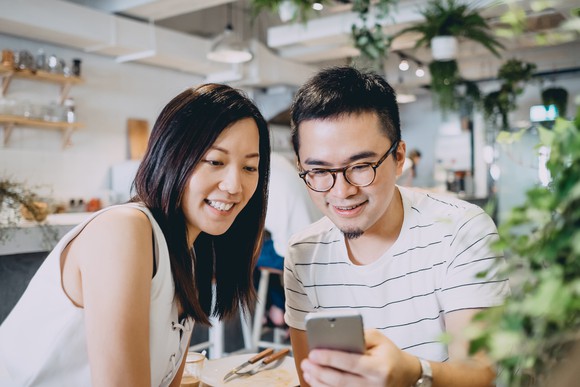 Two smiling people looking at a smartphone.