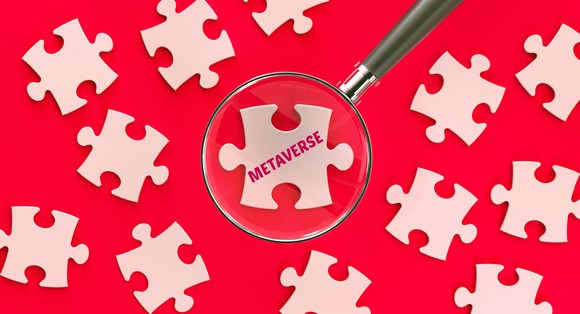 A magnifying glass over a jigsaw puzzle piece with "metaverse" printed on it with other blank jigsaw puzzle pices.