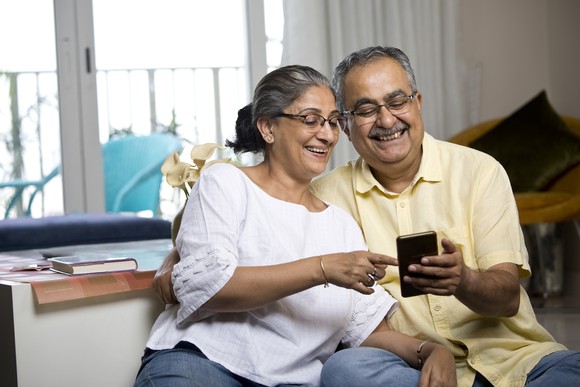 Two people looking at a smartphone and smiling.