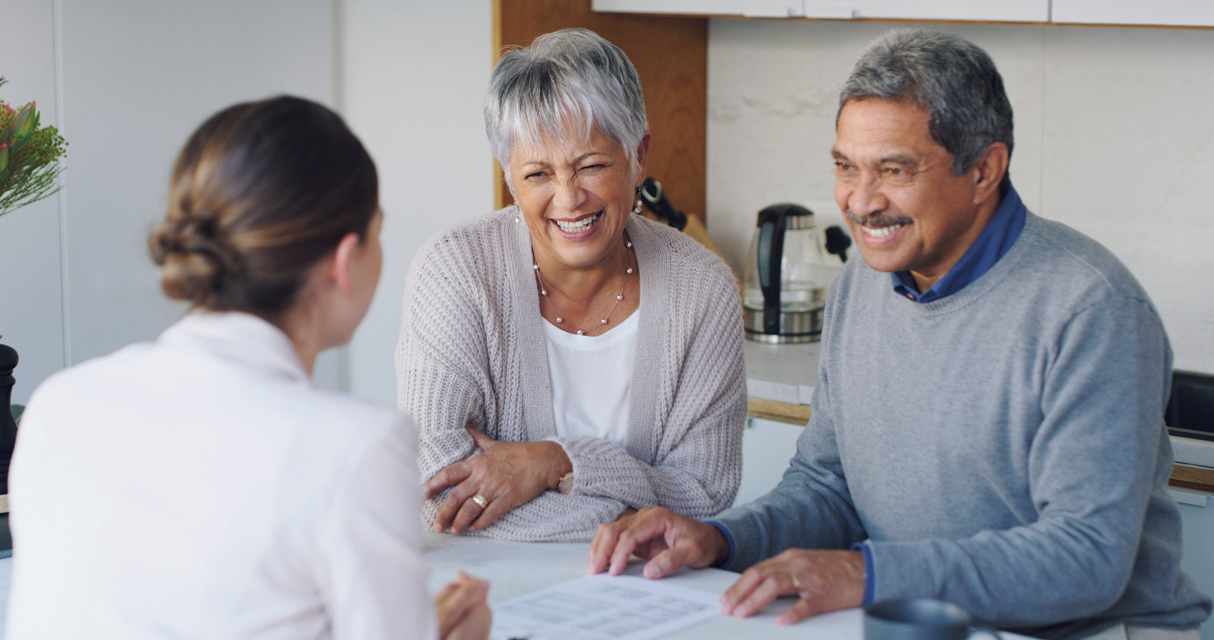 Senior couple smiling and discussing paperwork with consultant.