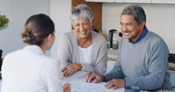 Senior couple smiling and discussing paperwork with consultant.