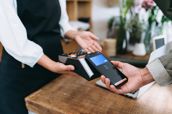 Closeup of customer holding phone to point-of-sale machine. 