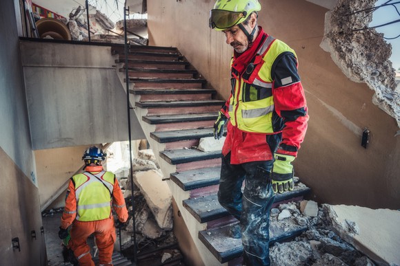 Two people search the rubble of a building after a hurricane