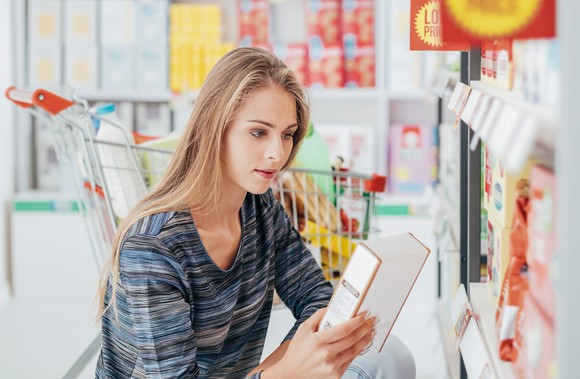 Young woman looking at a food product while grocery shopping