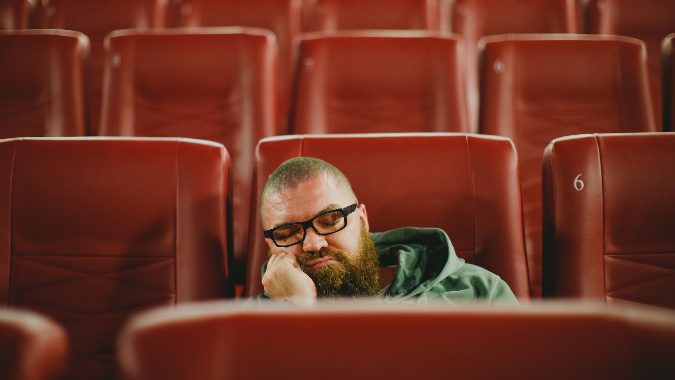 Moviegoer asleep in empty theater.