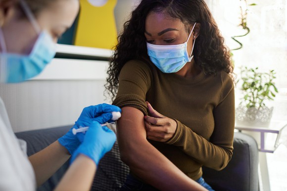 A healthcare worker vaccinates a person in an office setting.