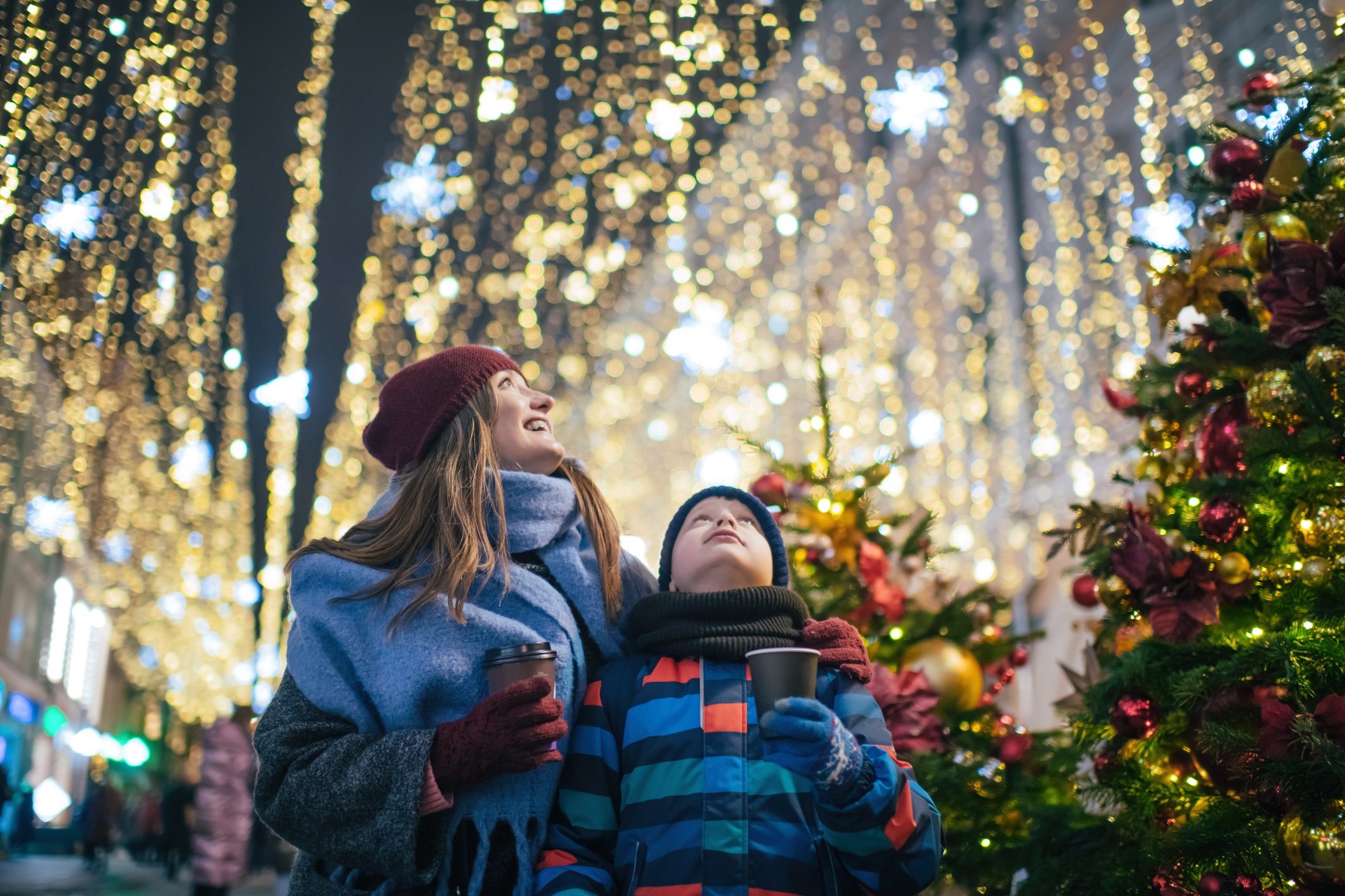 Person and child looking up at holiday lights. 