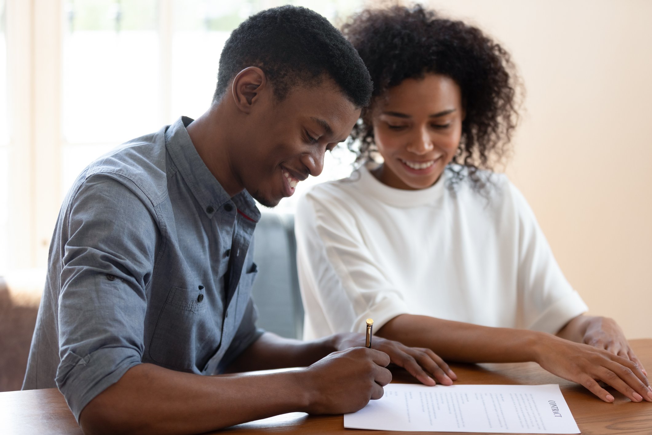 People signing mortgage papers and smiling.