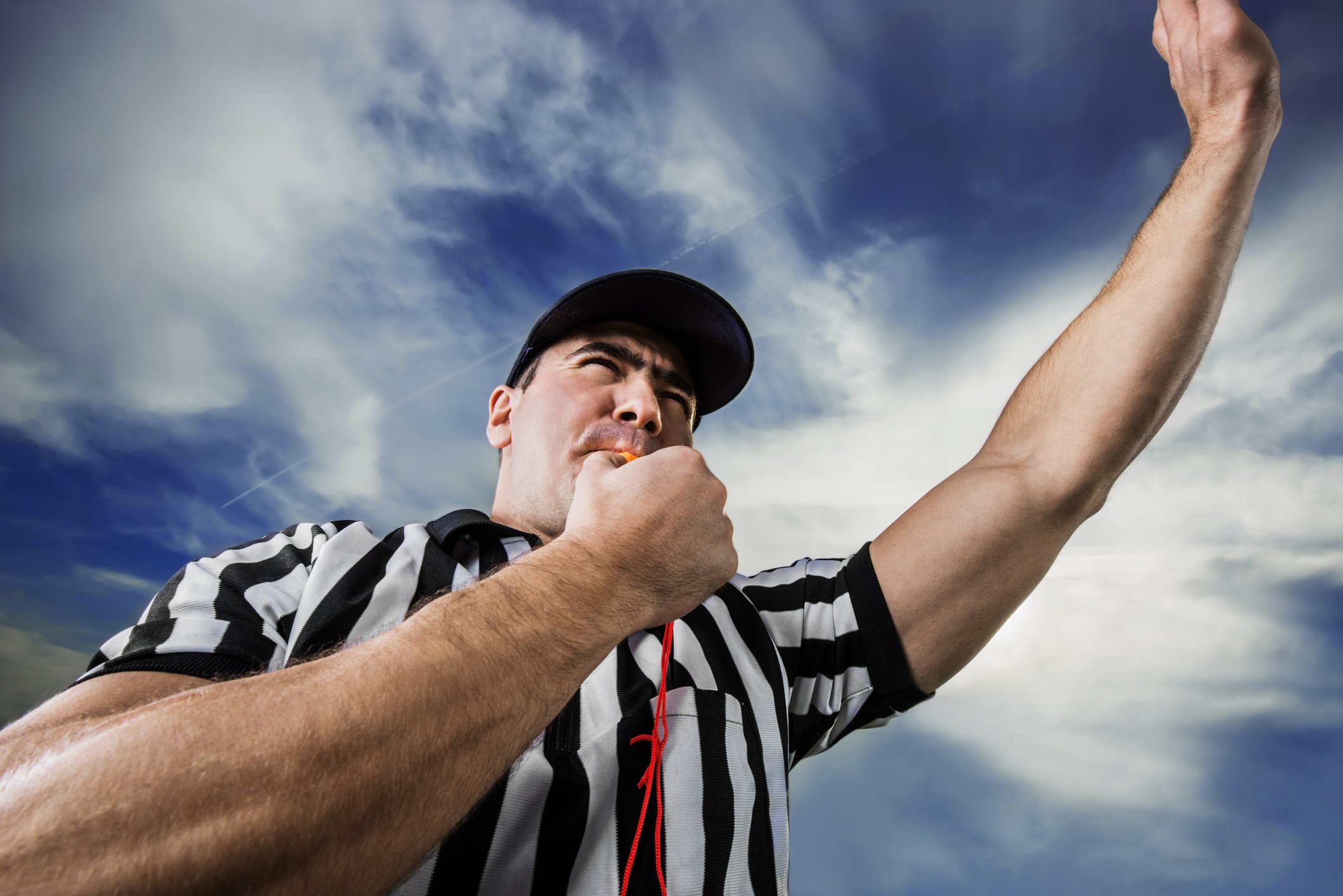 Referee blowing a whistle and pointing up.