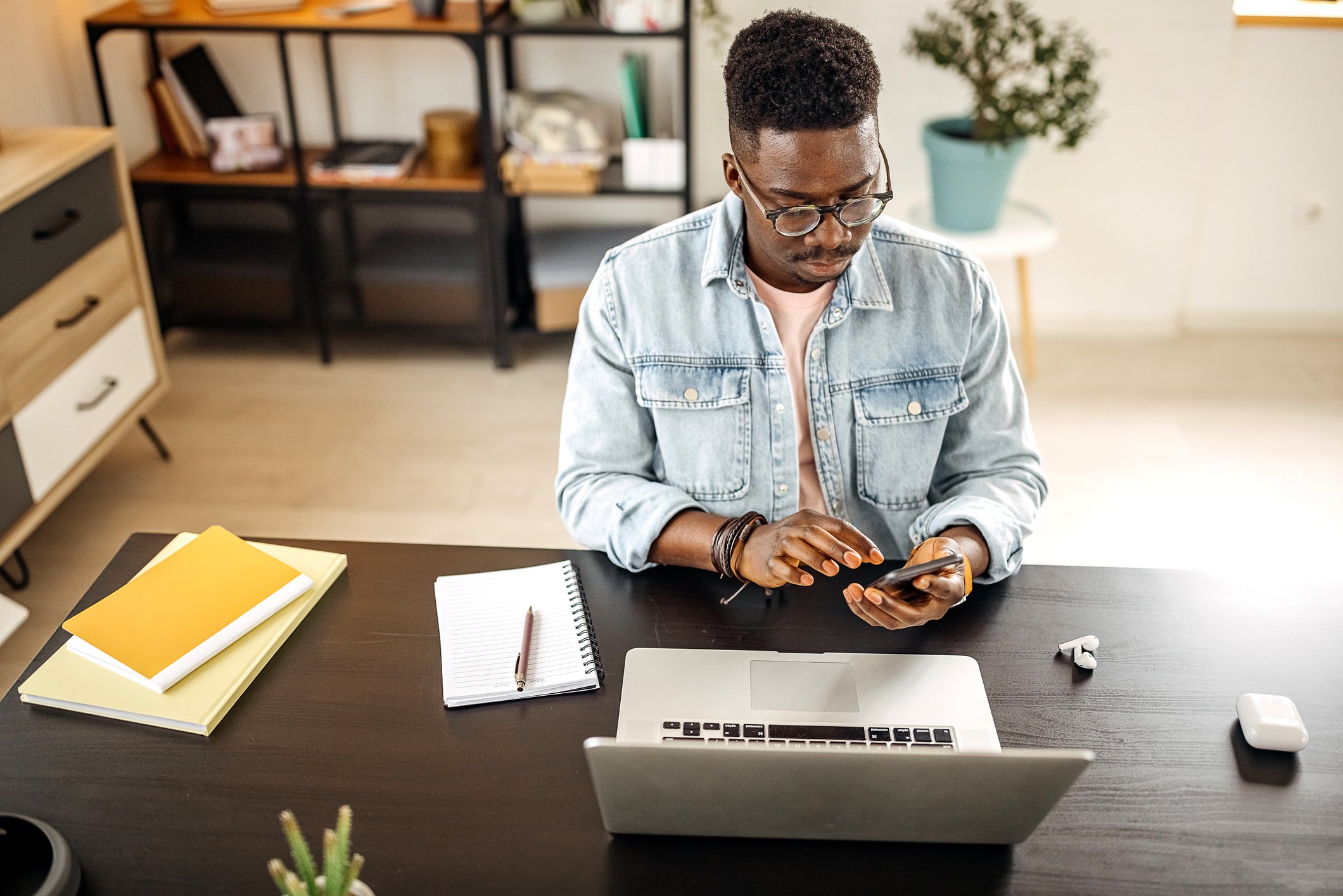 Person checking their crypto portfolio on a phone and sitting at a desk with work supplies.