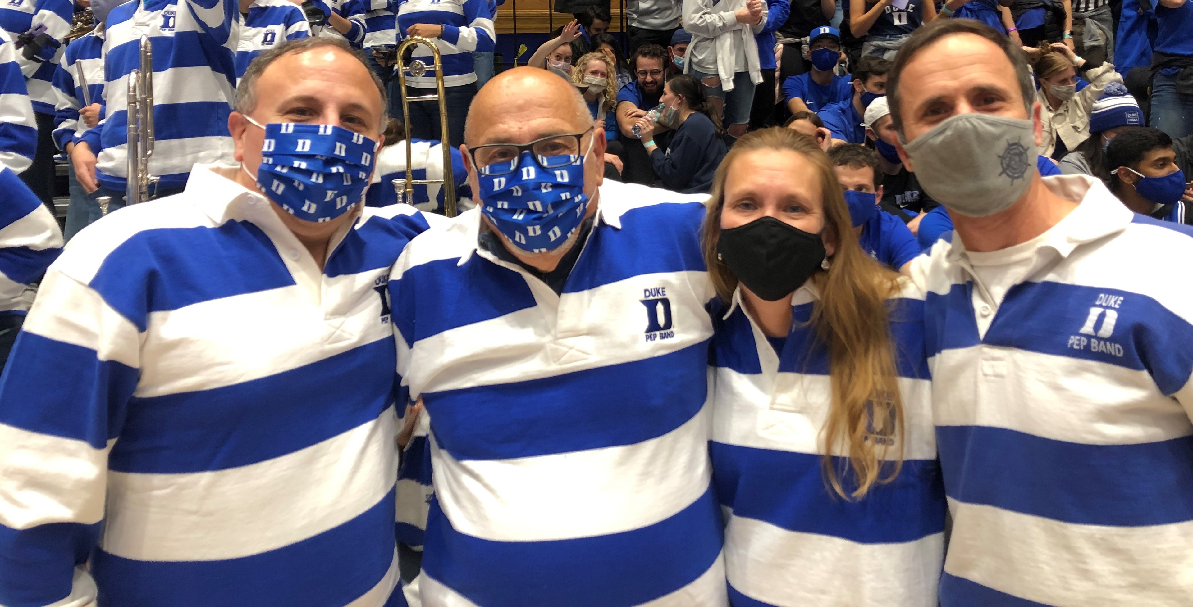 Four people wearing blue and white striped rugby shirts stand in a basketball arena.